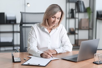 Photo of Businesswoman taking notes at table in office