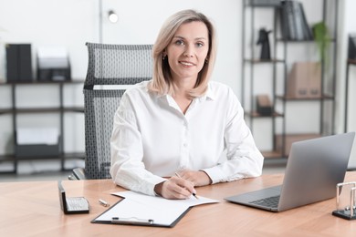 Photo of Businesswoman taking notes at table in office