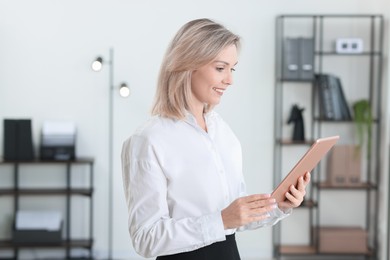 Portrait of happy businesswoman using tablet in office