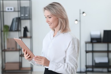 Photo of Portrait of happy businesswoman using tablet in office