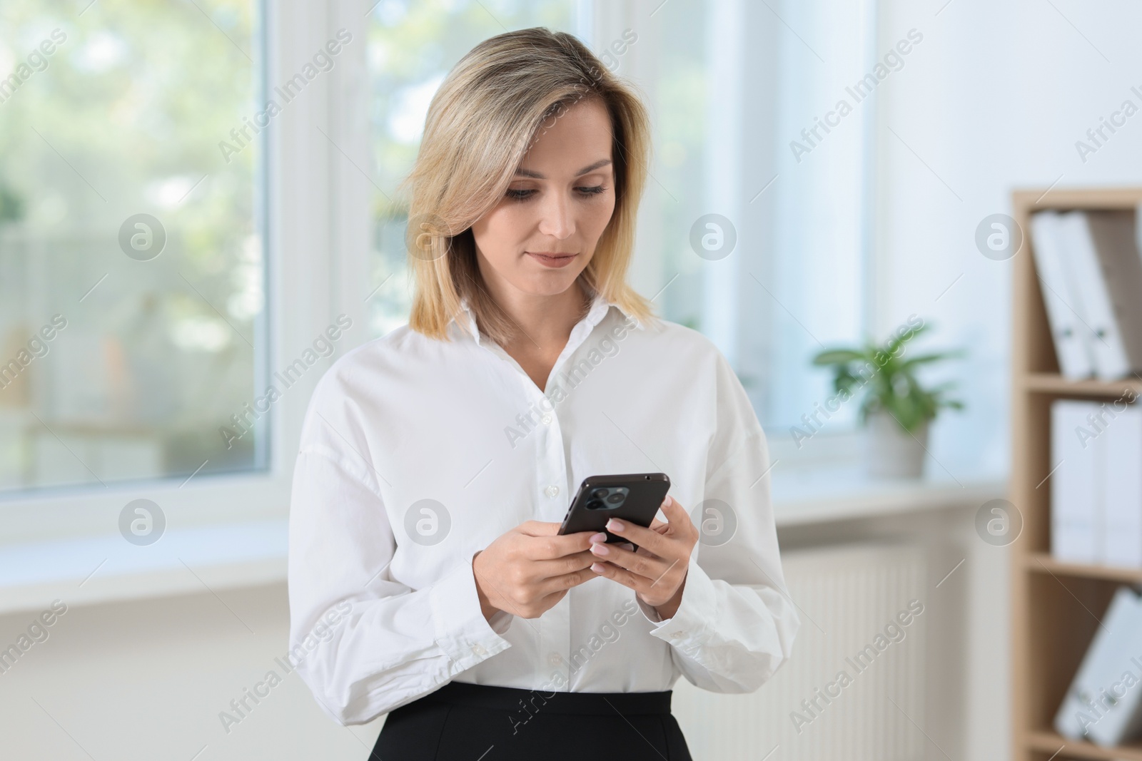 Photo of Portrait of businesswoman using smartphone in office