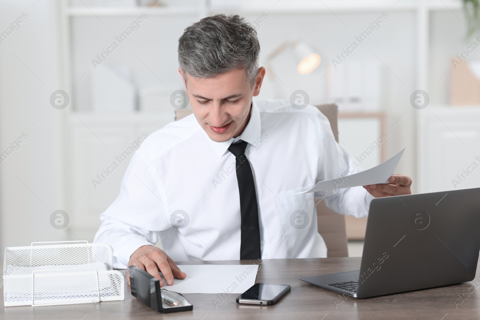 Photo of Businessman working with documents at table in office