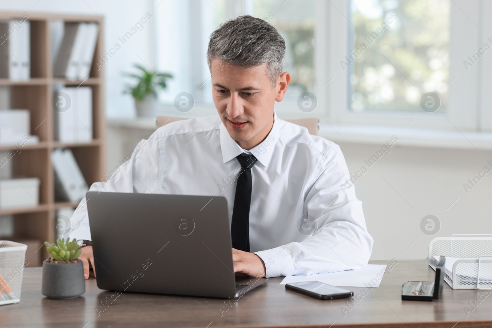 Photo of Businessman working with laptop at table in office