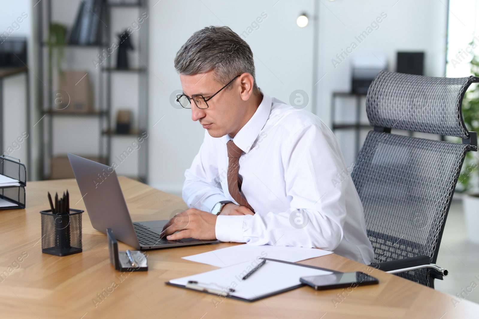 Photo of Businessman working on laptop at table in office