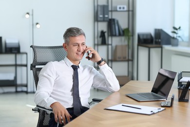 Businessman talking on smartphone at table in office