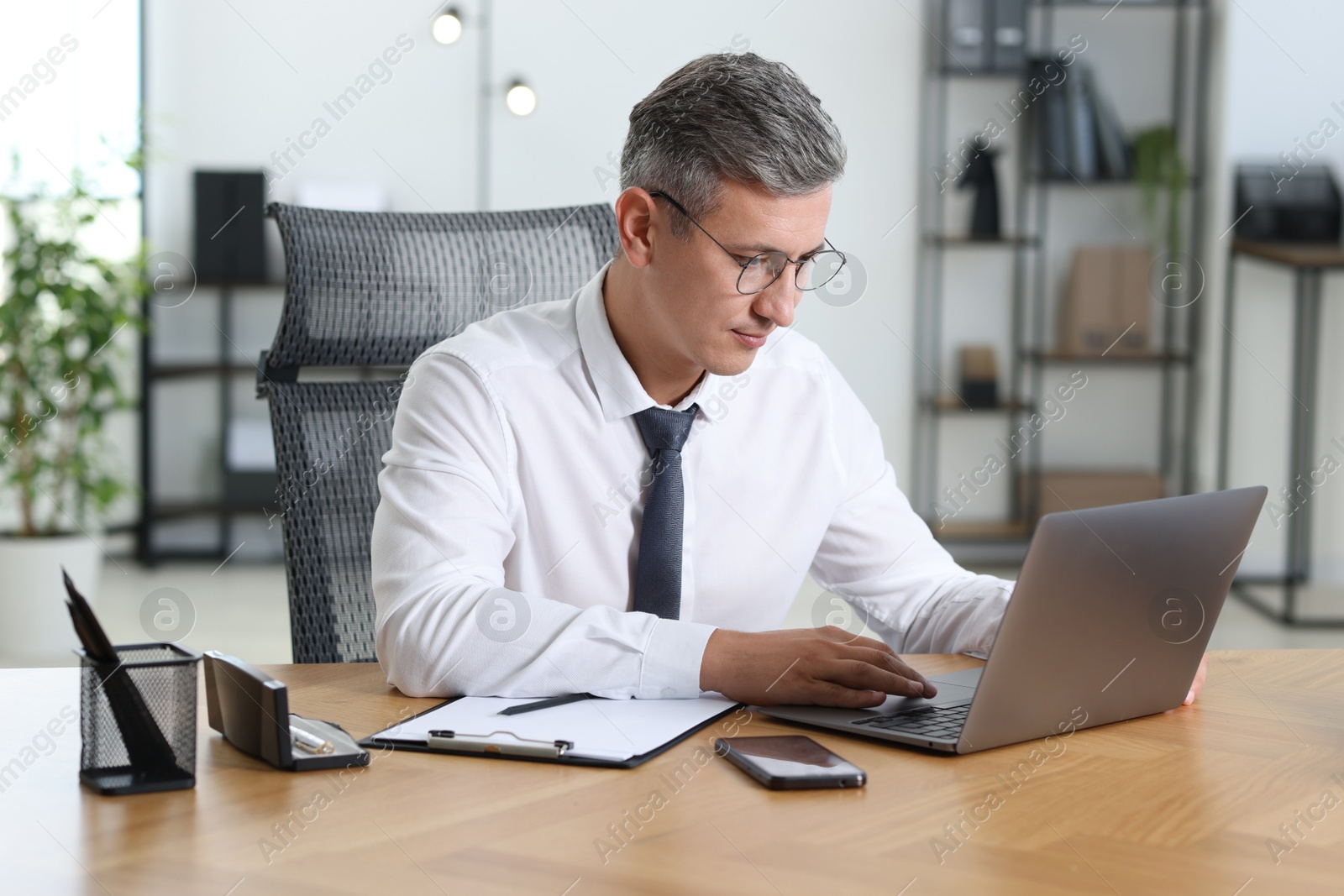 Photo of Businessman working on laptop at table in office