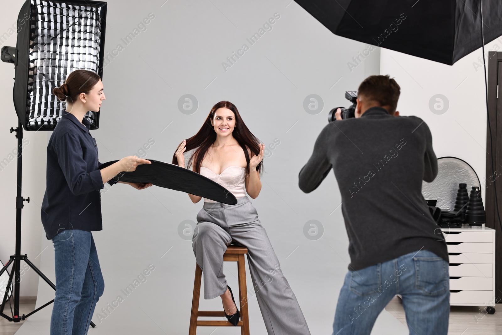 Photo of Photographer and assistant working with model in professional photo studio