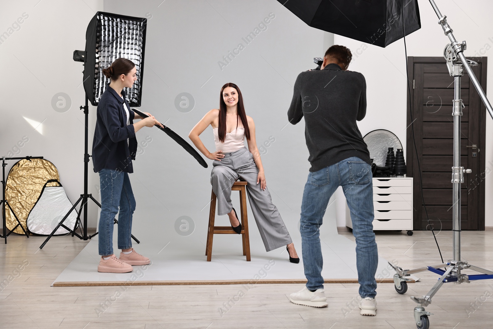 Photo of Photographer and assistant working with model in professional photo studio