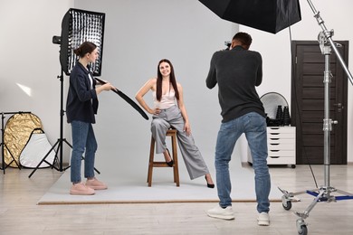 Photo of Photographer and assistant working with model in professional photo studio