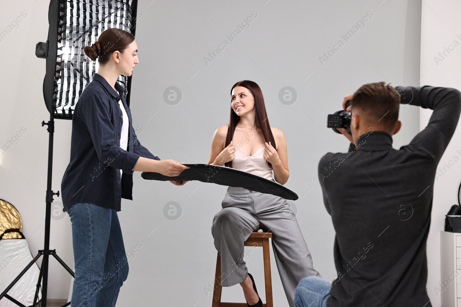 Photo of Photographer and assistant working with model in professional photo studio