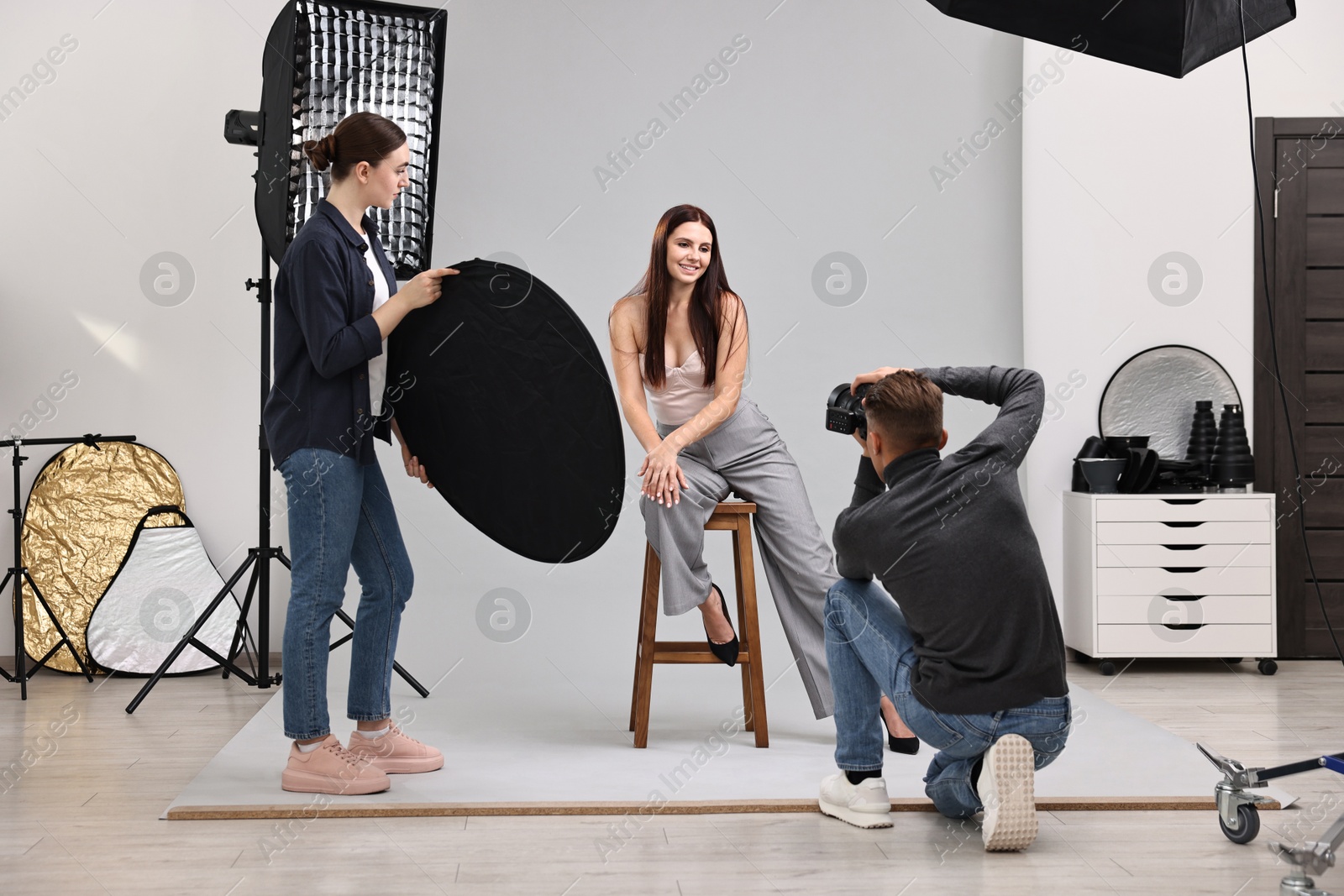 Photo of Photographer and assistant working with model in professional photo studio