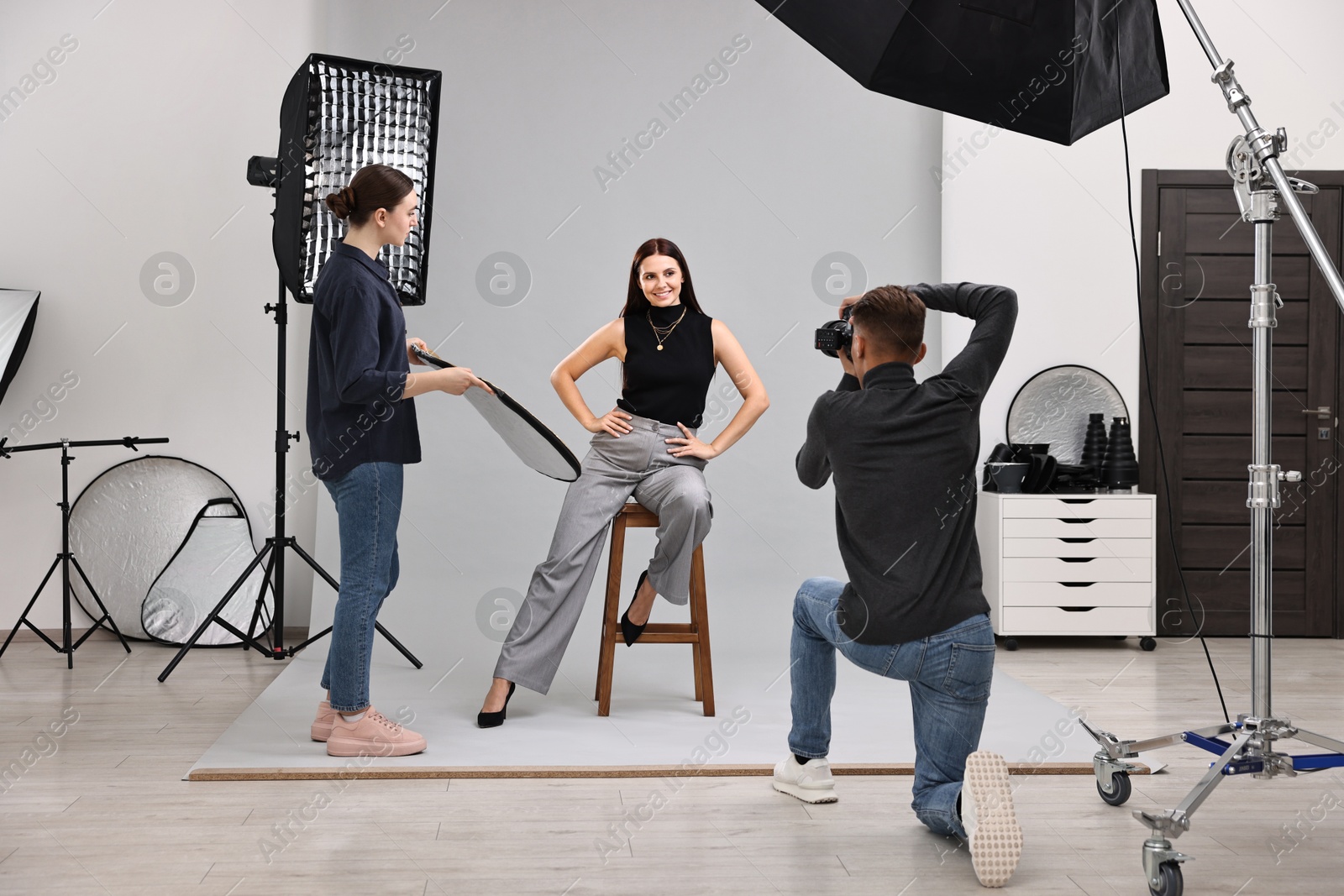 Photo of Photographer and assistant working with model in professional photo studio