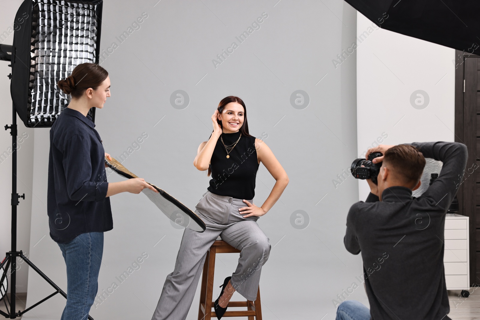 Photo of Photographer and assistant working with model in professional photo studio