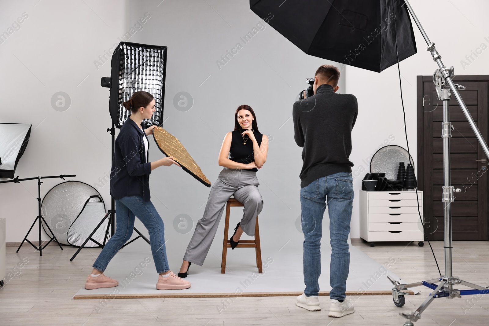 Photo of Photographer and assistant working with model in professional photo studio