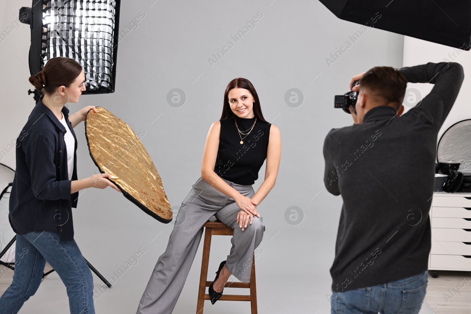 Photo of Photographer and assistant working with model in professional photo studio