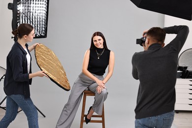 Photo of Photographer and assistant working with model in professional photo studio