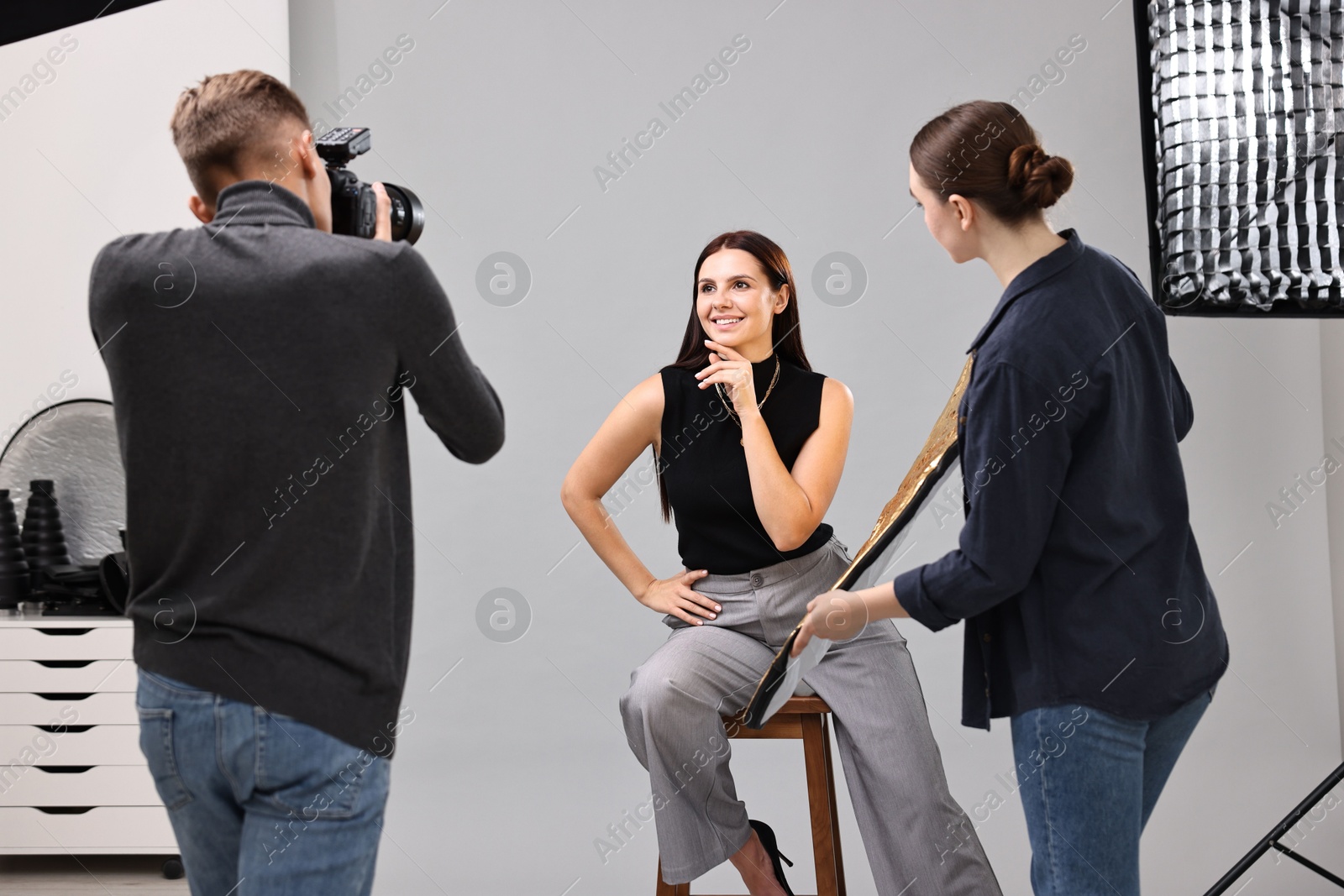 Photo of Photographer and assistant working with model in professional photo studio