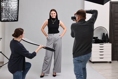 Photo of Photographer and assistant working with model in professional photo studio