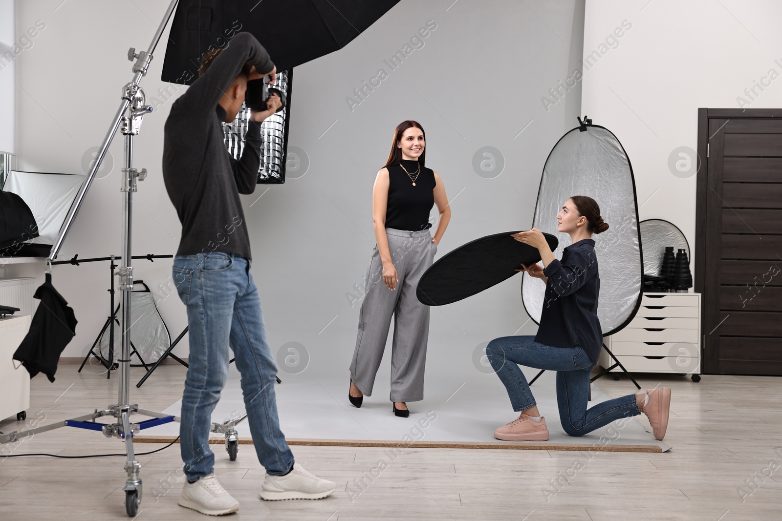 Photo of Photographer and assistant working with model in professional photo studio