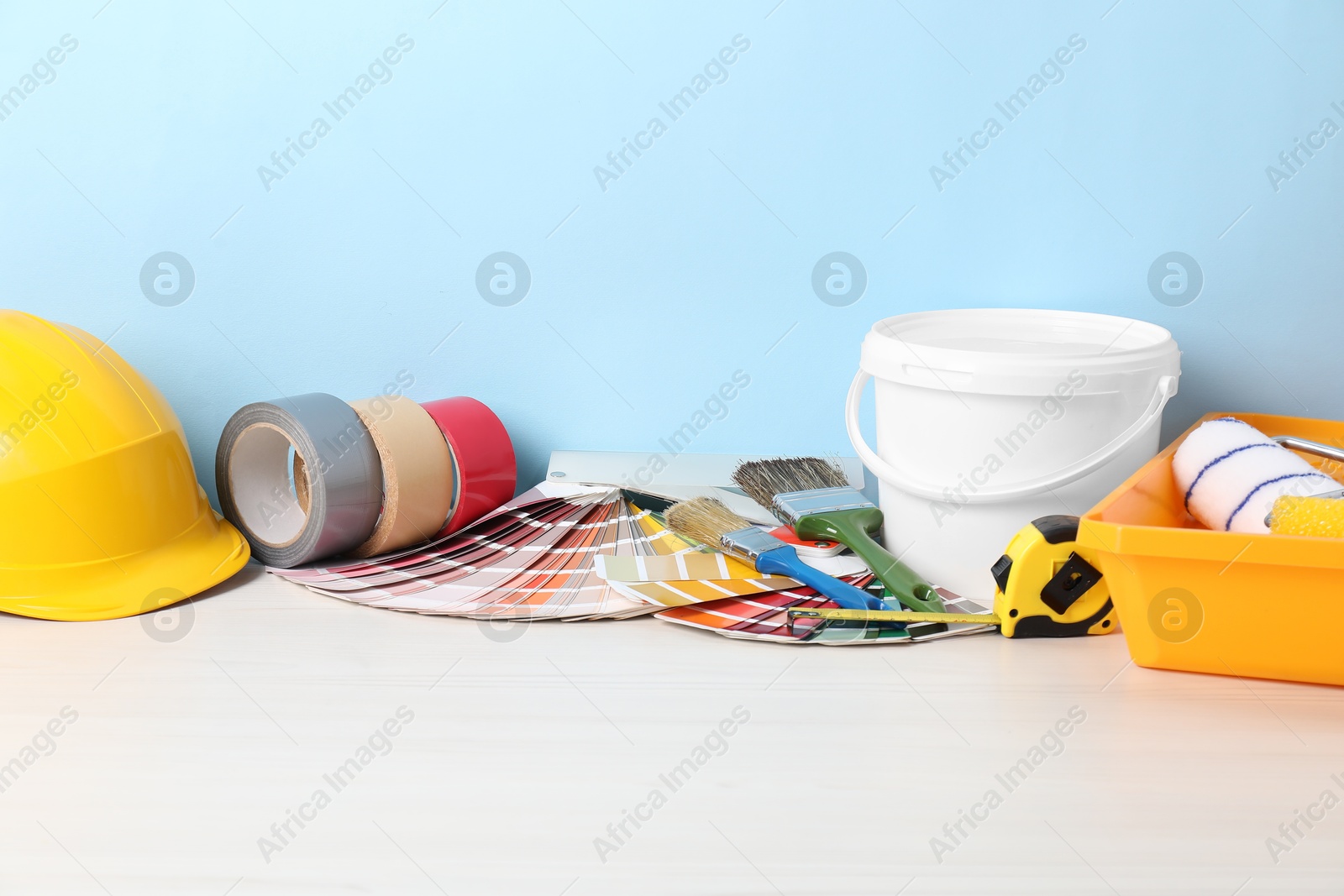 Photo of Different painter's tools on white wooden table. Decorating and design