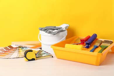 Photo of Different painter's tools on white wooden table. Decorating and design