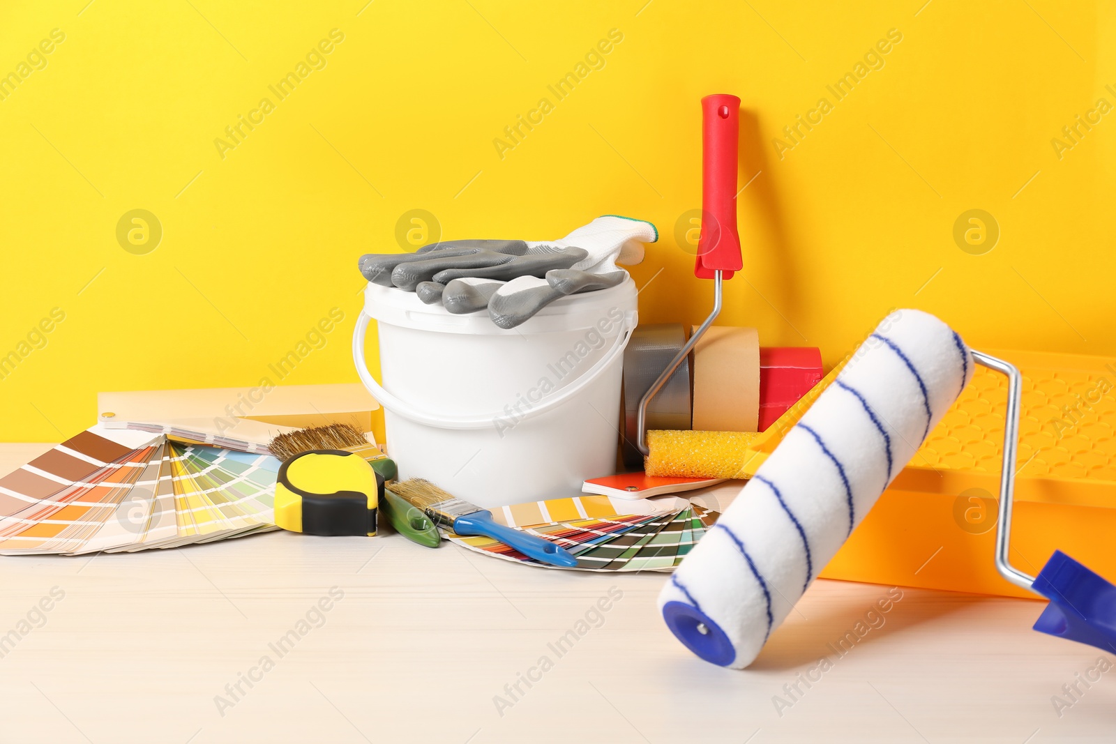 Photo of Different painter's tools on white wooden table. Decorating and design