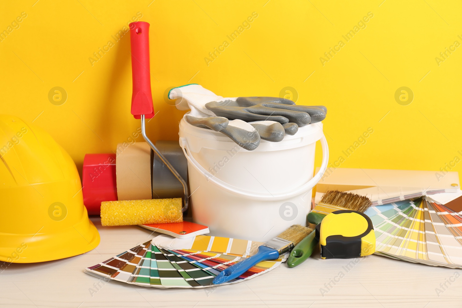 Photo of Different painter's tools on white wooden table. Decorating and design