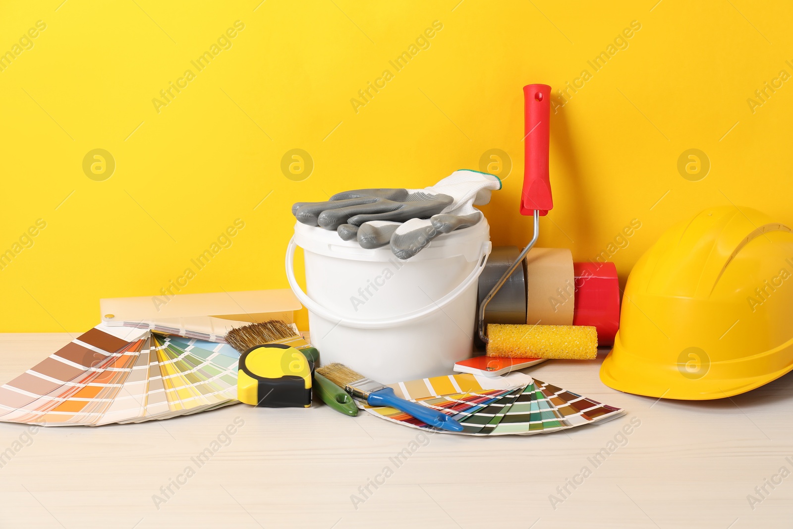 Photo of Different painter's tools on white wooden table. Decorating and design