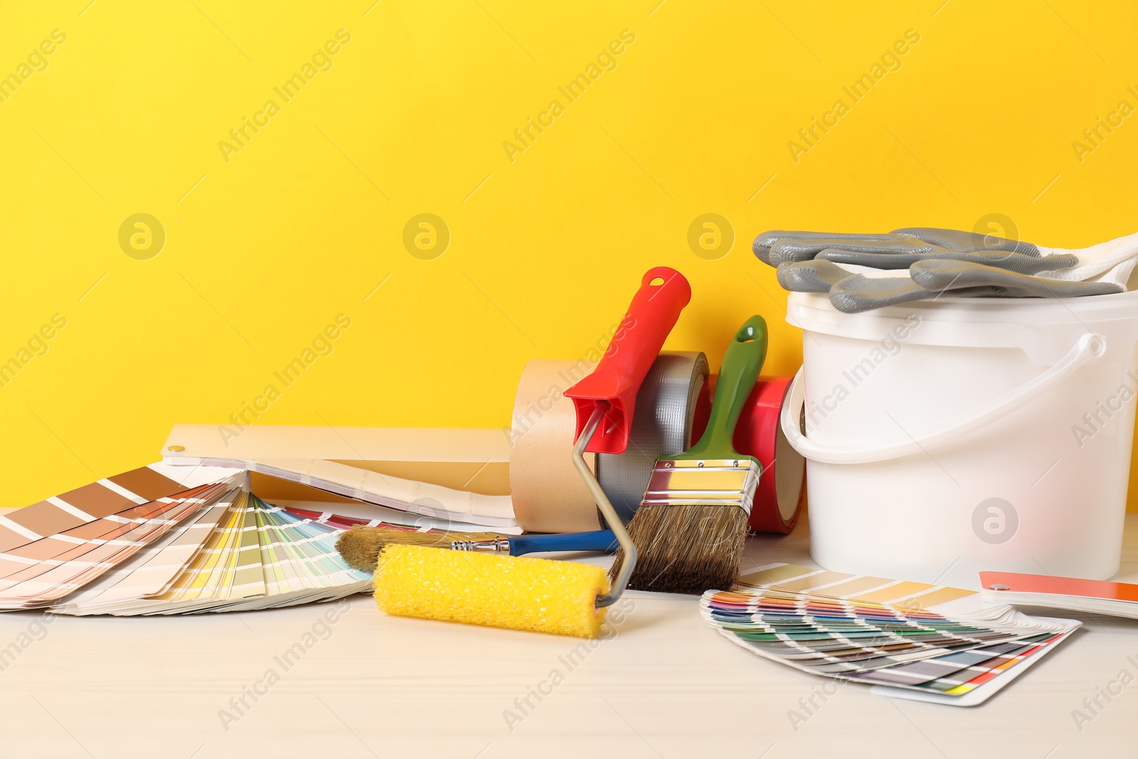 Photo of Different painter's tools on white wooden table. Decorating and design