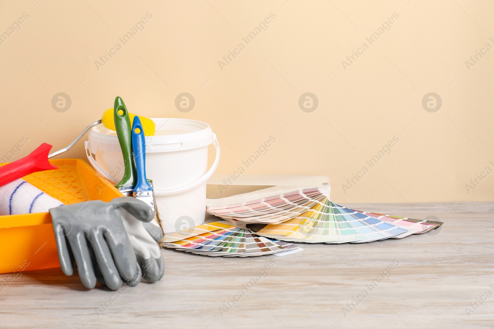 Photo of Different painter's tools on light wooden table, space for text. Decorating and design