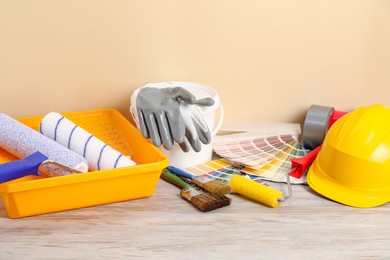 Photo of Different painter's tools on light wooden table. Decorating and design