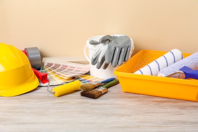 Photo of Different painter's tools on light wooden table. Decorating and design