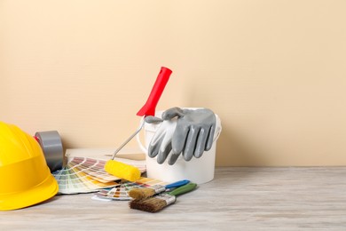 Photo of Different painter's tools on light wooden table, space for text. Decorating and design