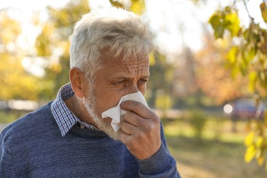 Photo of Senior man with runny nose in park, space for text