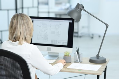 Photo of Technician making digital engineering drawing on computer at desk in office, back view