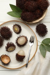 Photo of Delicious ripe rambutans served on white wooden table, flat lay