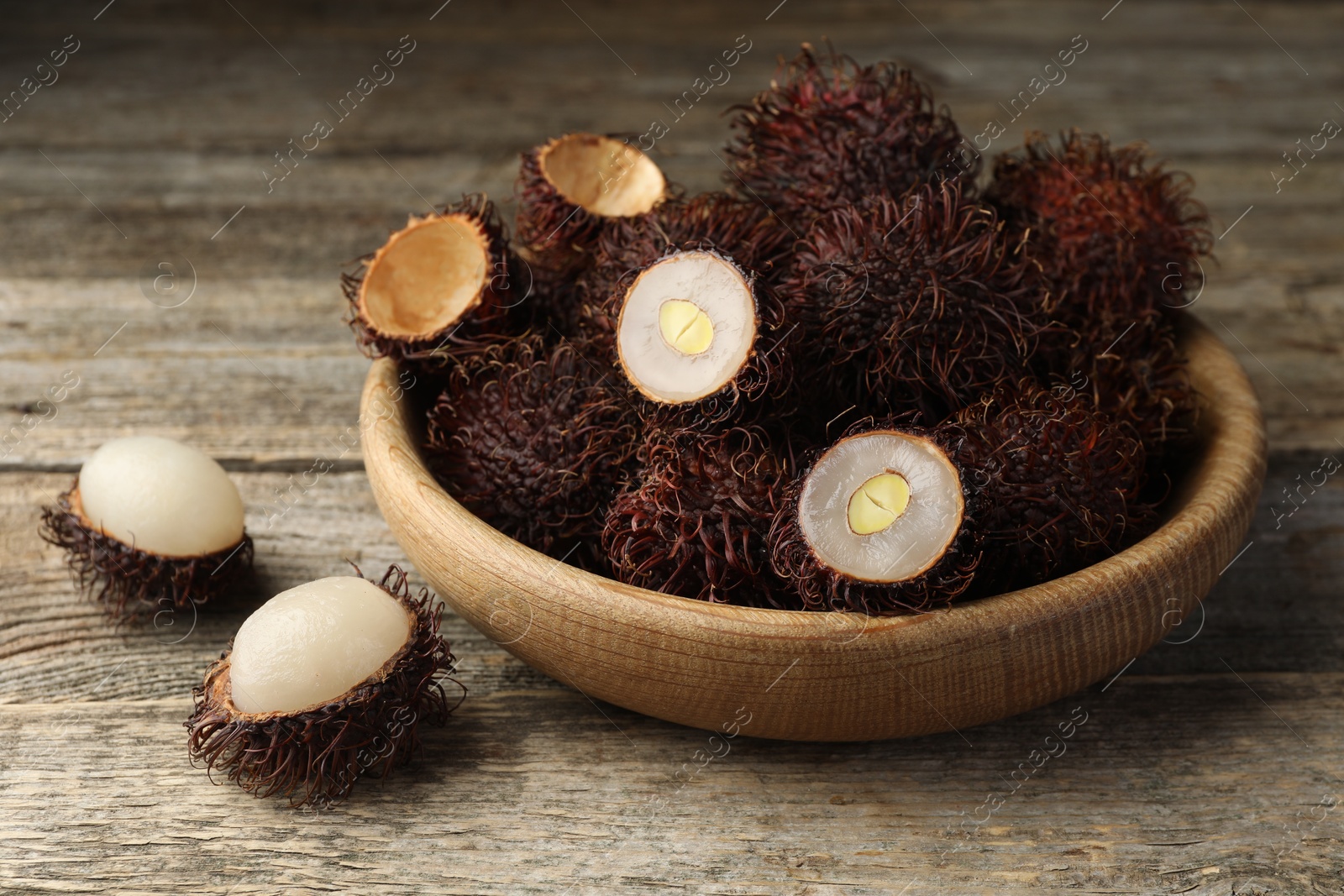 Photo of Delicious ripe rambutans on wooden table, closeup