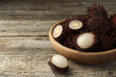 Photo of Delicious ripe rambutans on wooden table, closeup. Space for text