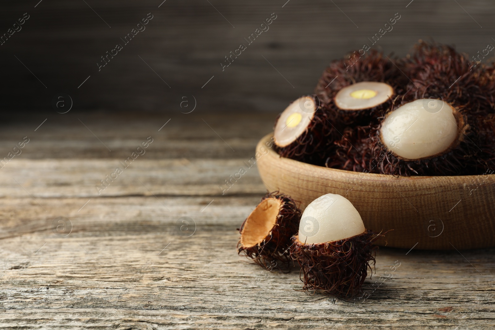 Photo of Delicious ripe rambutans on wooden table, closeup. Space for text