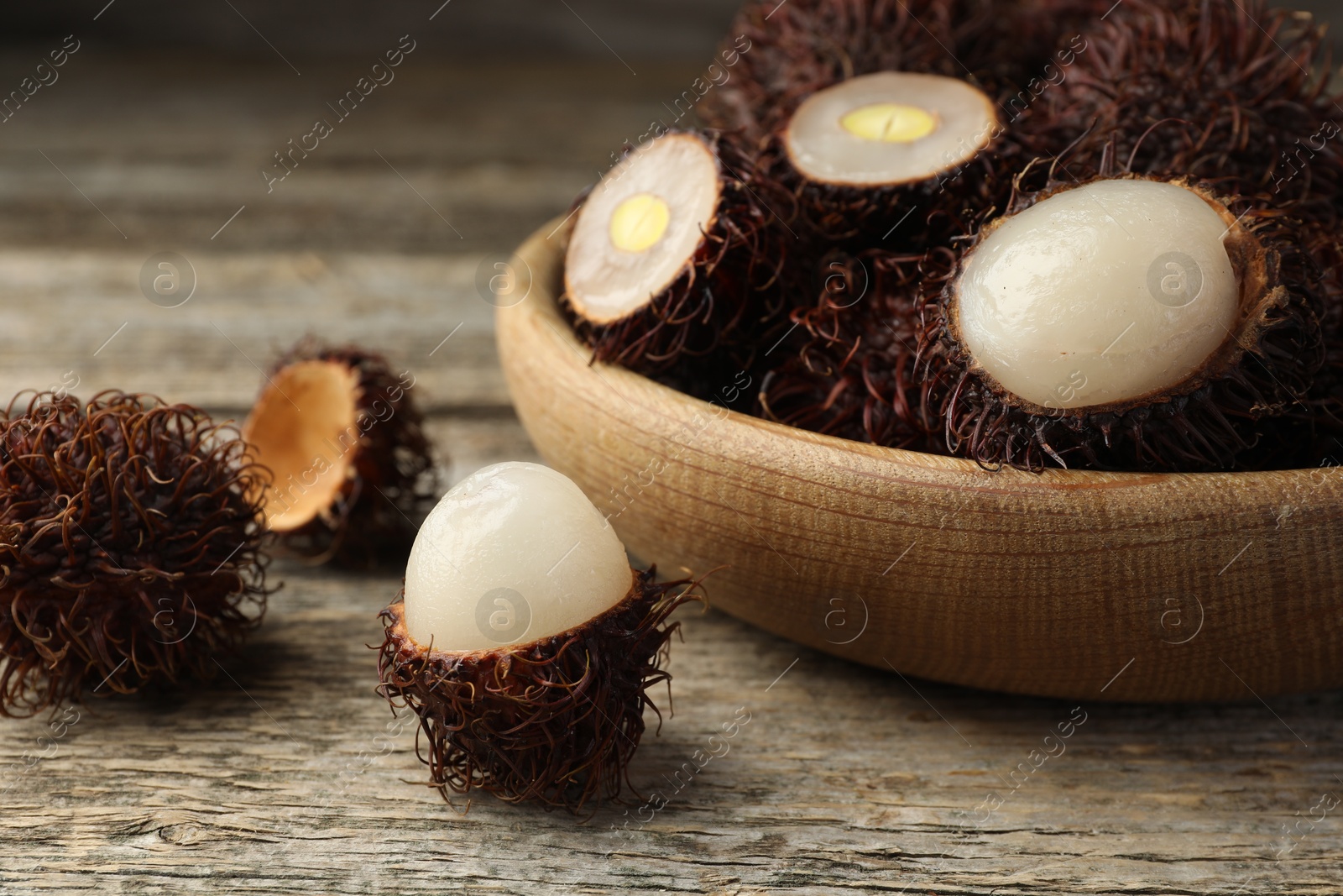 Photo of Delicious ripe rambutans on wooden table, closeup