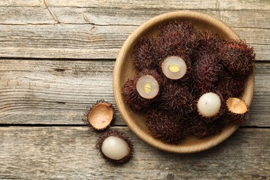 Photo of Delicious ripe rambutans on wooden table, top view. Space for text