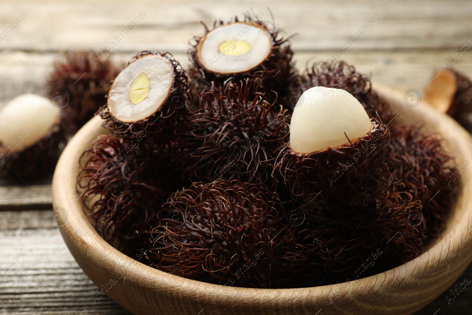 Photo of Delicious ripe rambutans on wooden table, closeup