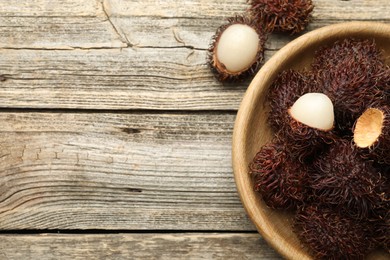 Photo of Delicious ripe rambutans on wooden table, top view. Space for text