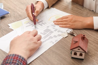 Real estate agent working with client at wooden table, closeup