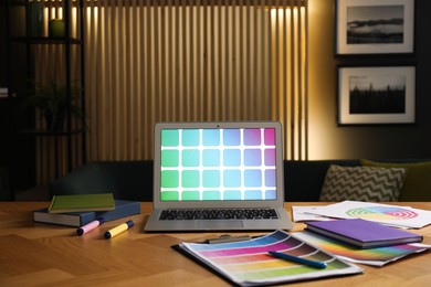 Photo of Designer's workplace with laptop, stationery and palettes on wooden table indoors