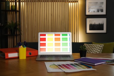 Photo of Designer's workplace with laptop, stationery and palettes on wooden table indoors