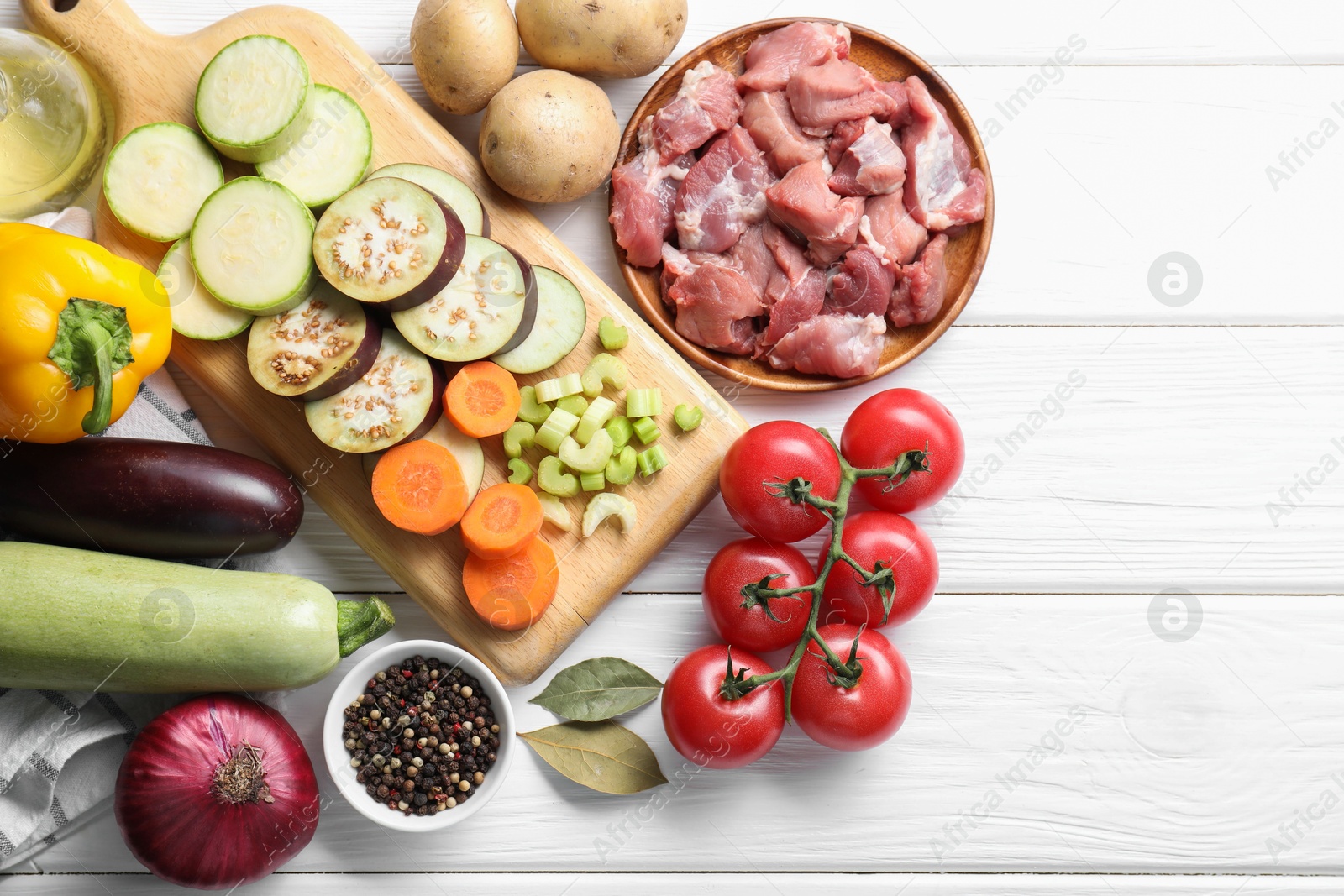 Photo of Cooking stew. Uncooked meat and vegetables on white wooden table, flat lay. Space for text