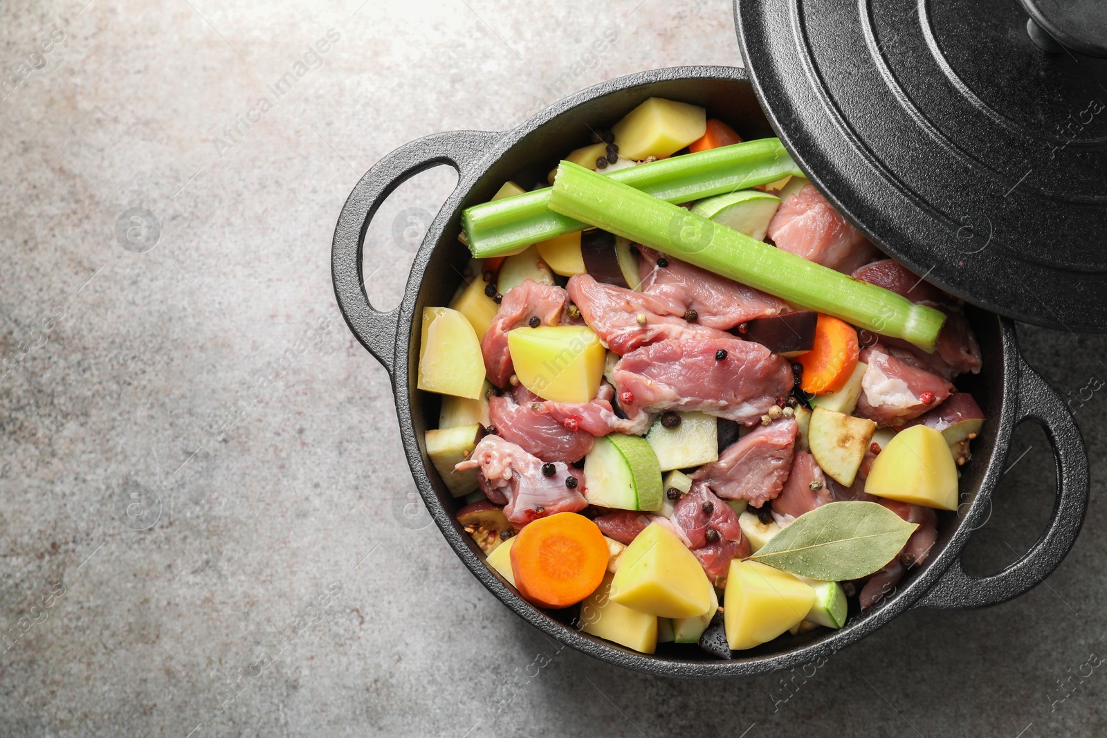 Photo of Cooking stew. Uncooked meat and vegetables in pot on light grey table, top view. Space for text