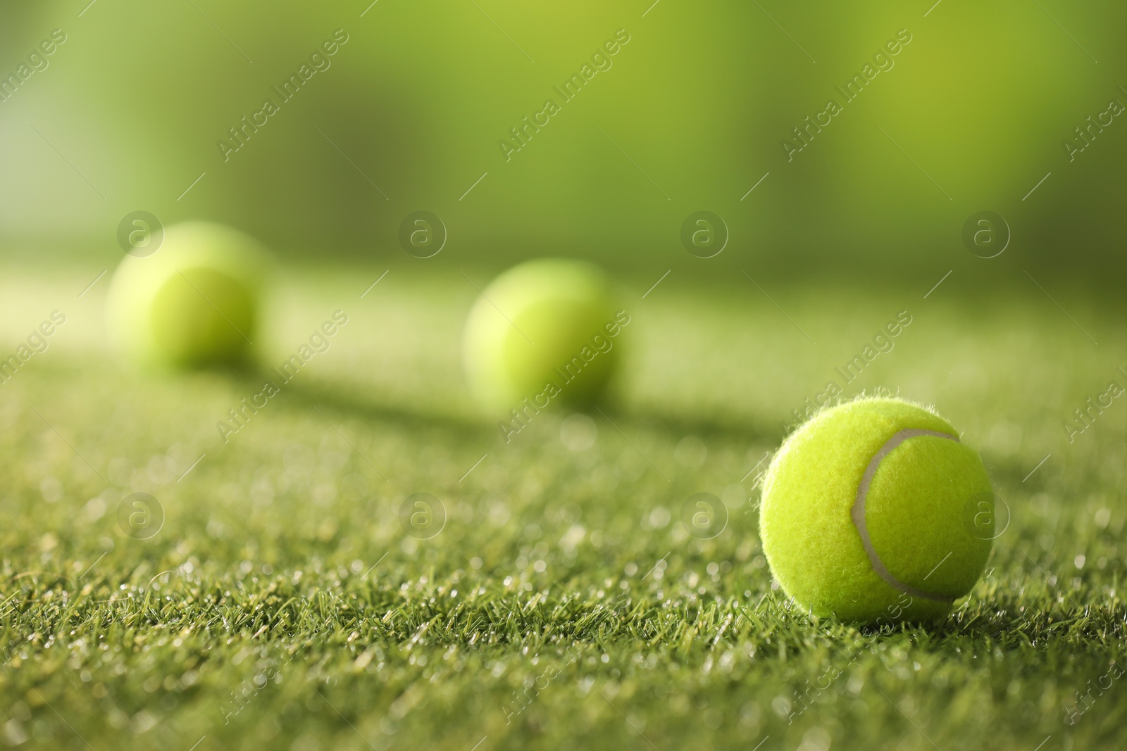 Photo of Tennis balls on green artificial grass, selective focus