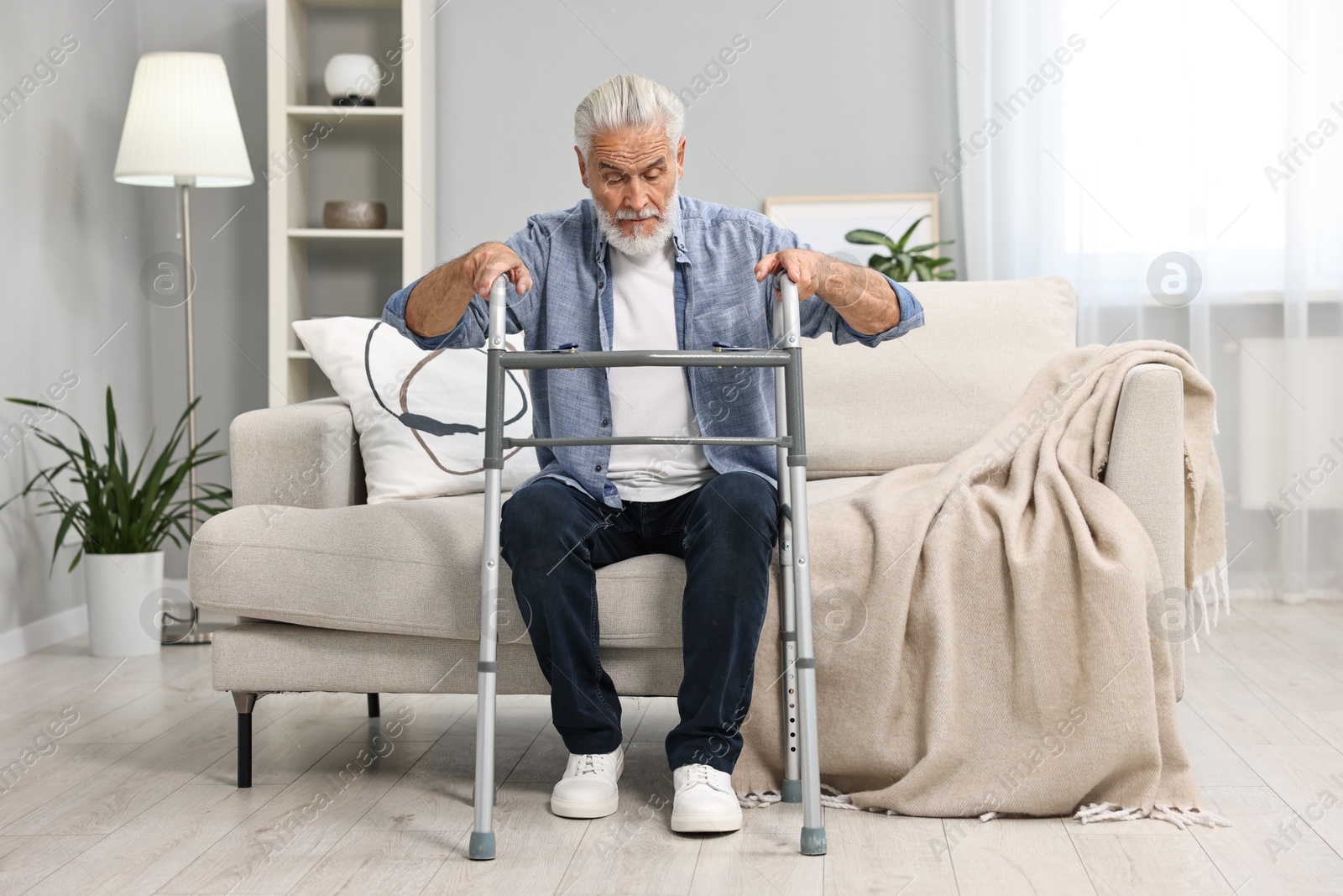 Photo of Senior man with walking frame on sofa at home